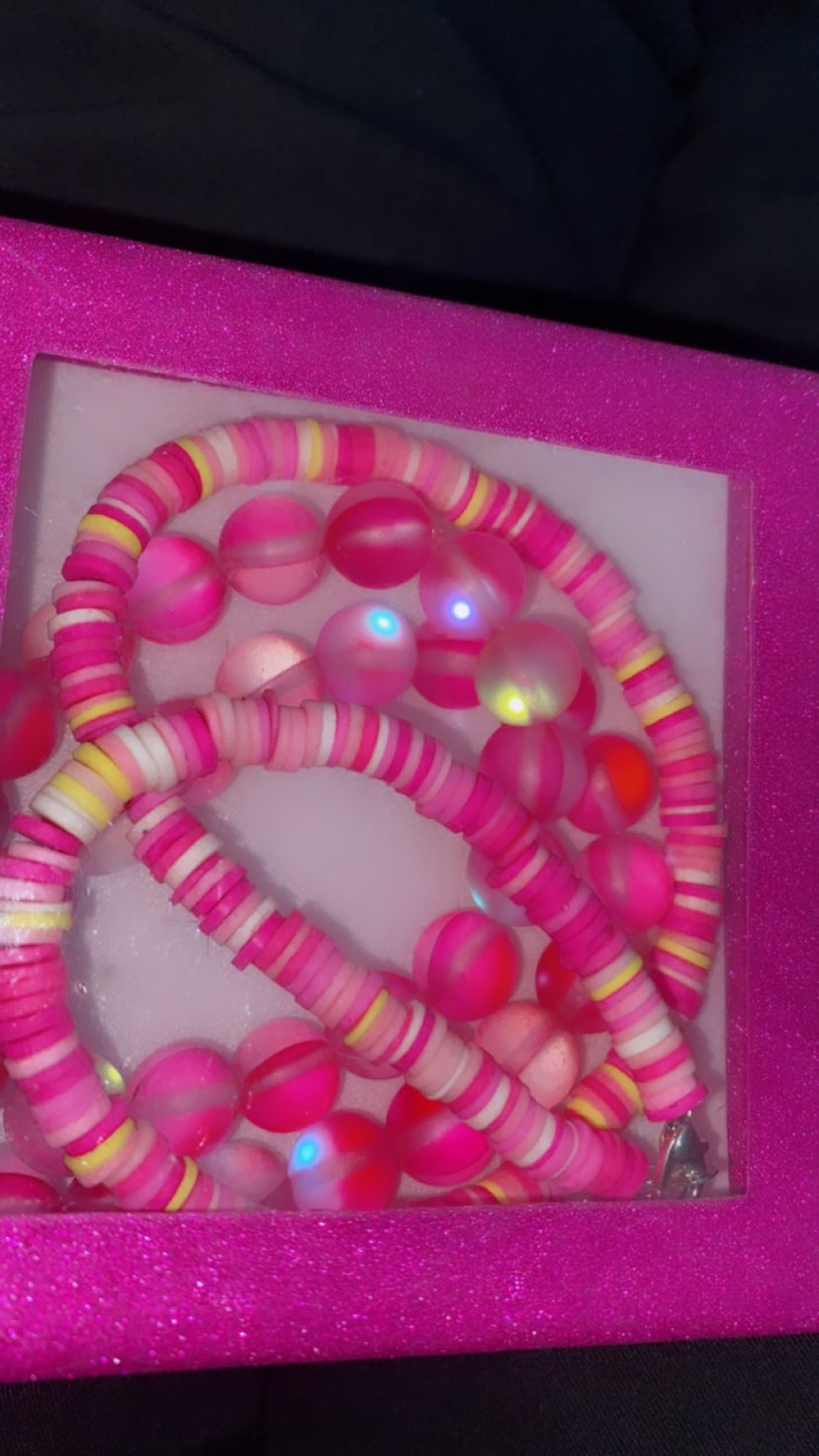 Close-up of a box of colorful beads, predominantly in shades of pink and yellow, on a box.